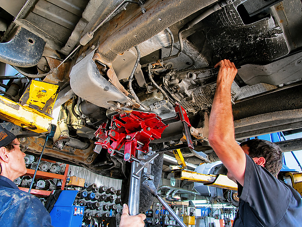 Techniciens travaillant sur une transmission sous un véhicule dans l’atelier